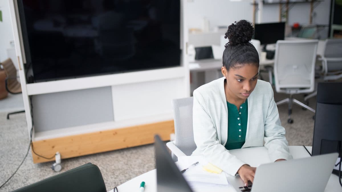 A businesswoman comparing options on a laptop in a modern office