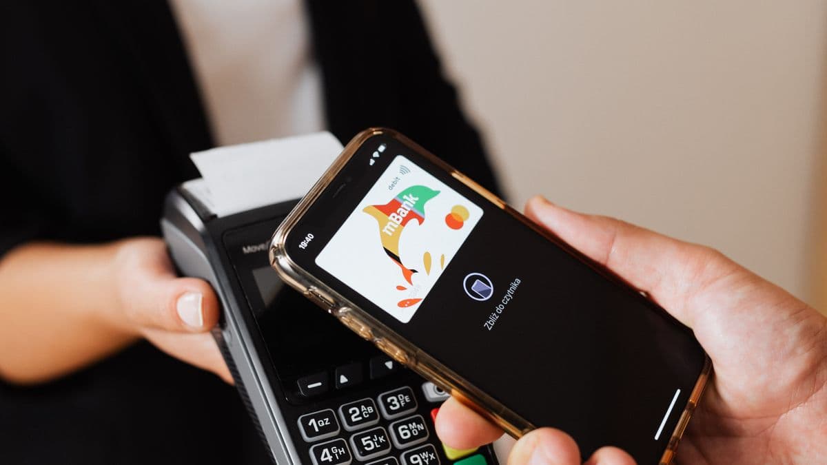 A hand holding a phone to pay at a card terminal