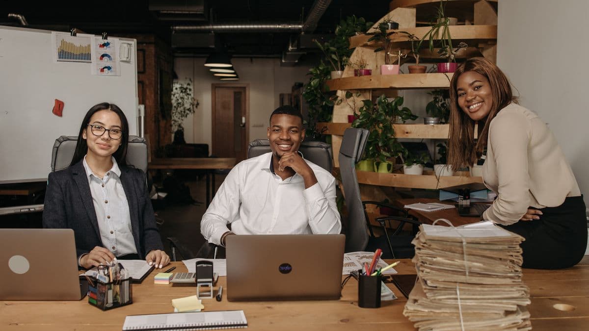Three young business professionals working with laptops in a modern office